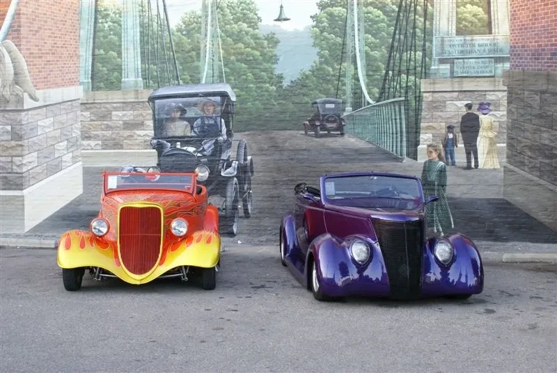 Vintage hot rods parked by brick building