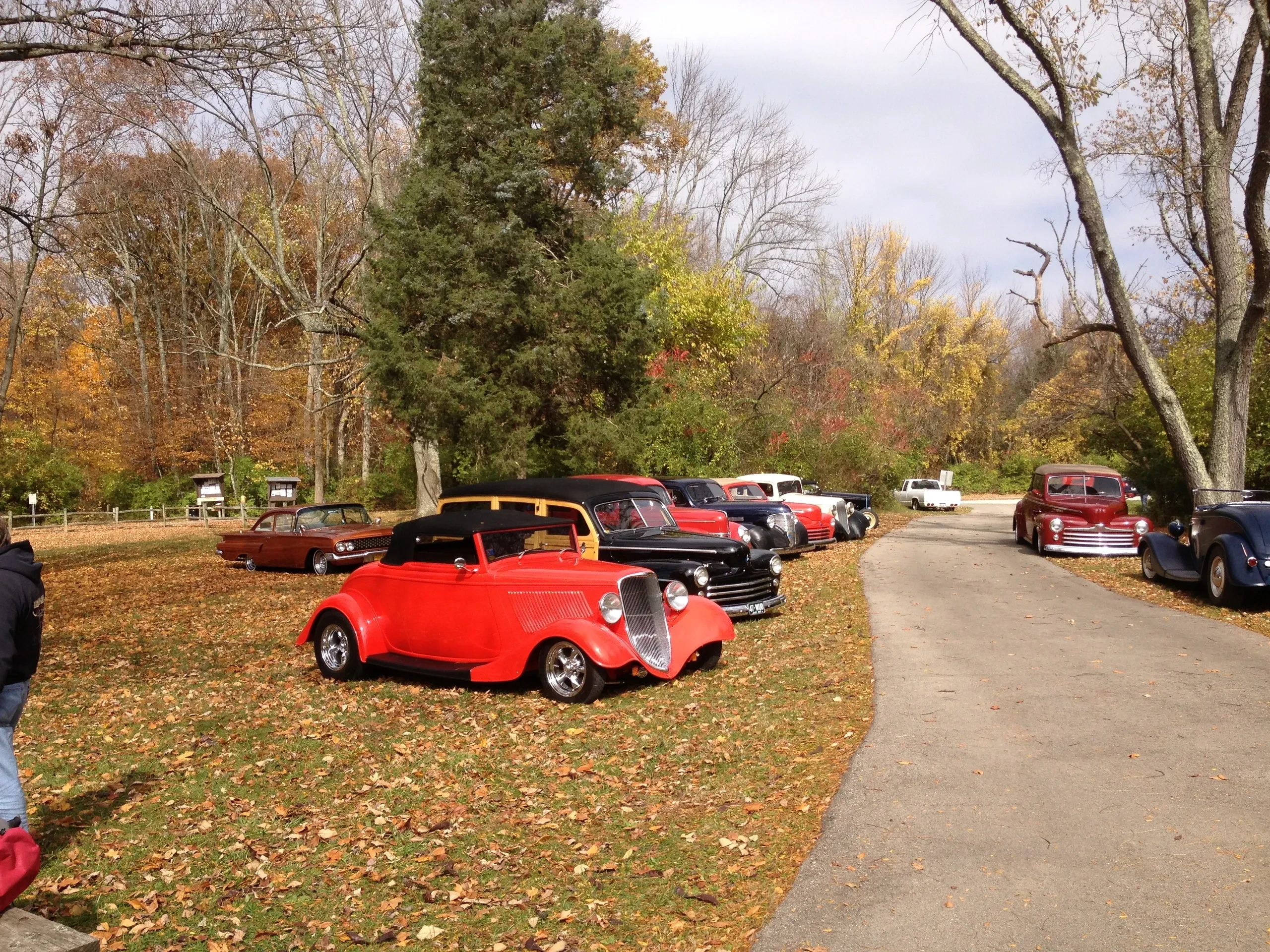 Red convertible and classic cars parked in autumn park