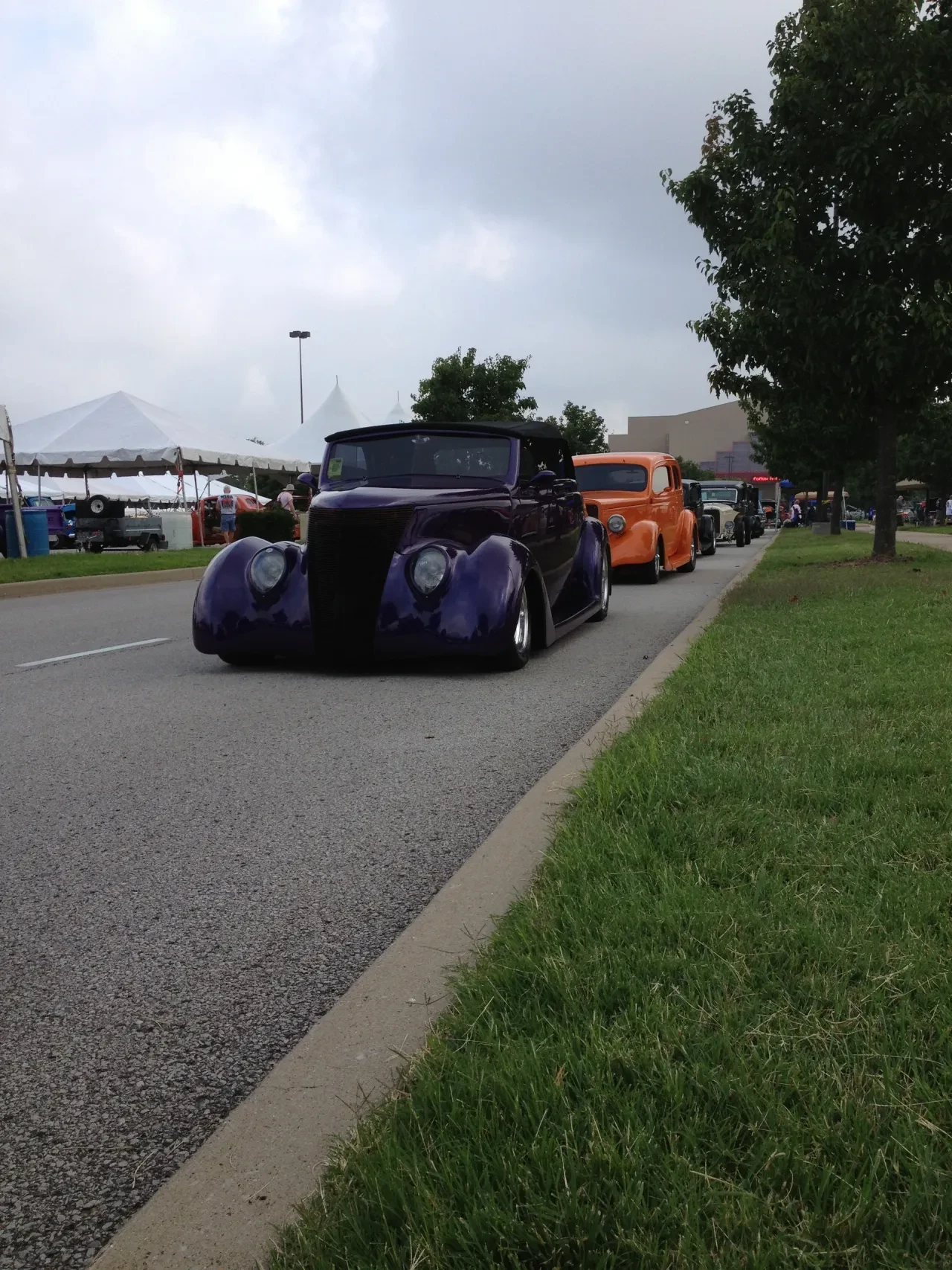 Purple hot rod leading a line of street rods