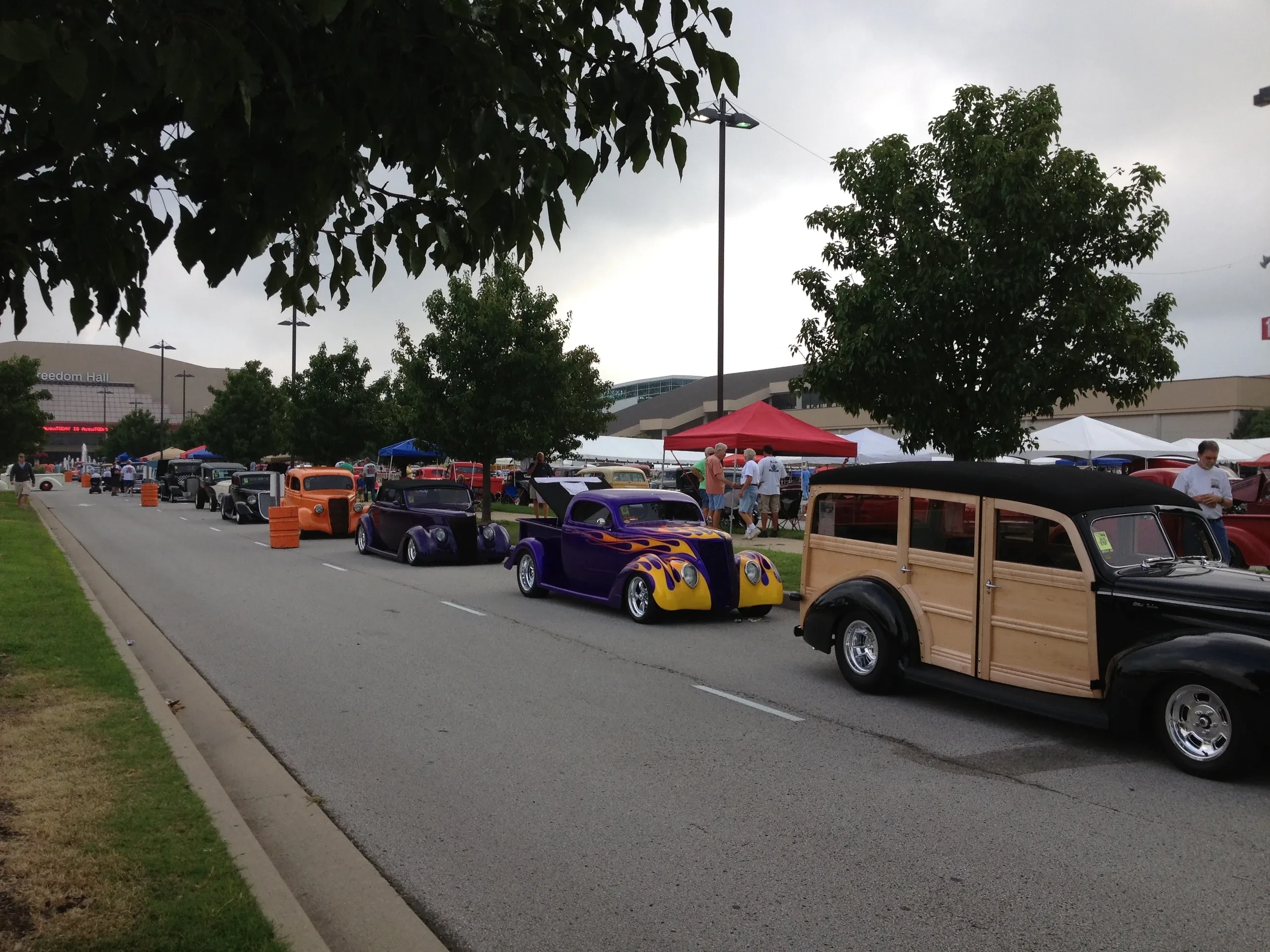 Street rods lined up at outdoor car show near Freedom Hall